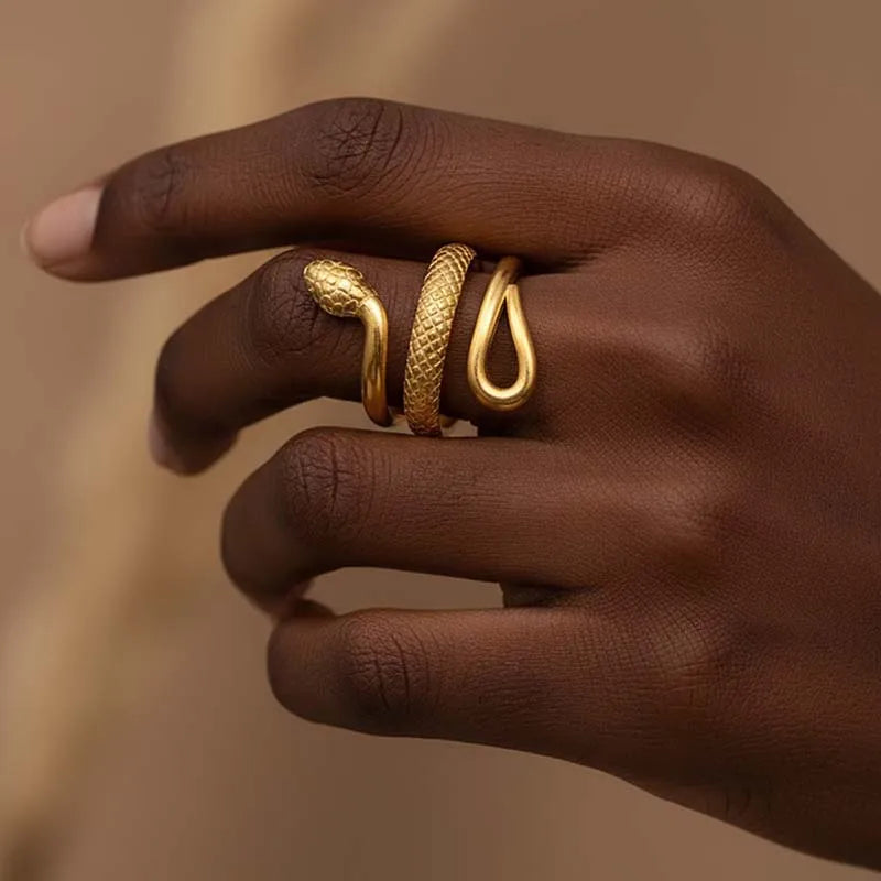 Adjustable serpent wrap ring in 18K gold plated stainless steel with detailed scale texture. Snake design coils around finger with smooth and textured sections. Hypoallergenic, waterproof, weighs 3.4g with 1.8cm width.