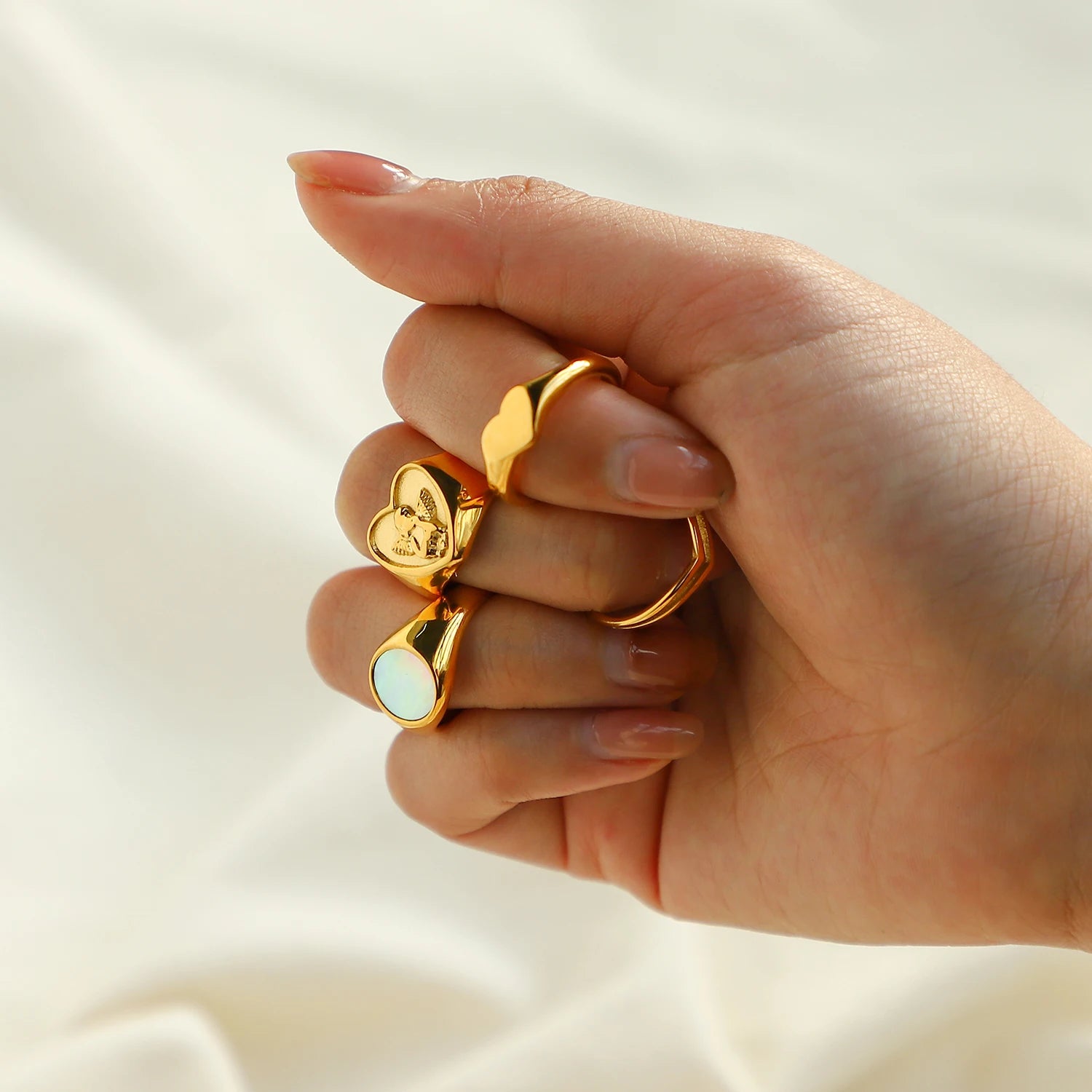 A chunky 18ct gold plated medical steel heart signet ring featuring a detailed embossed cherub (angel) on a textured gold background.