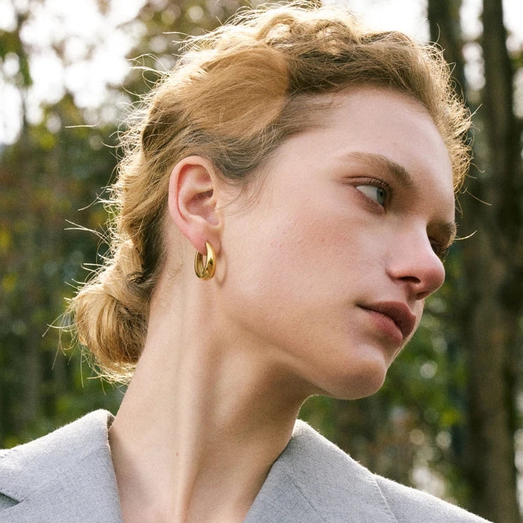 A pair of 18ct gold plated medical steel huggie hoop earrings featuring four interlocking bands, two plain gold and two with clear crystal pavé, creating a stacked look.