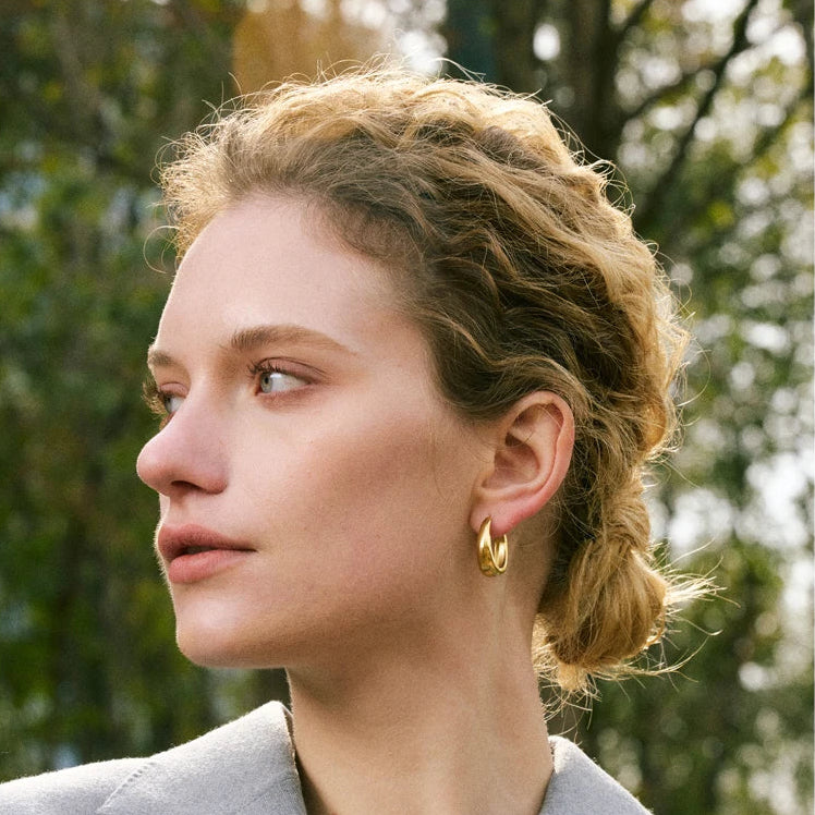 A pair of 18ct gold plated medical steel huggie hoop earrings featuring four interlocking bands, two plain gold and two with clear crystal pavé, creating a stacked look.