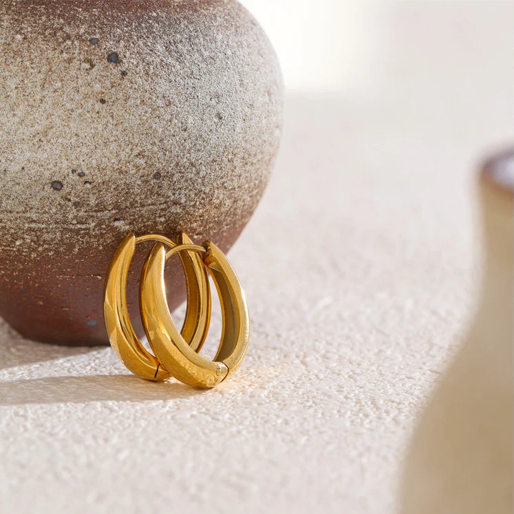 A pair of 18ct gold plated medical steel huggie hoop earrings featuring four interlocking bands, two plain gold and two with clear crystal pavé, creating a stacked look.