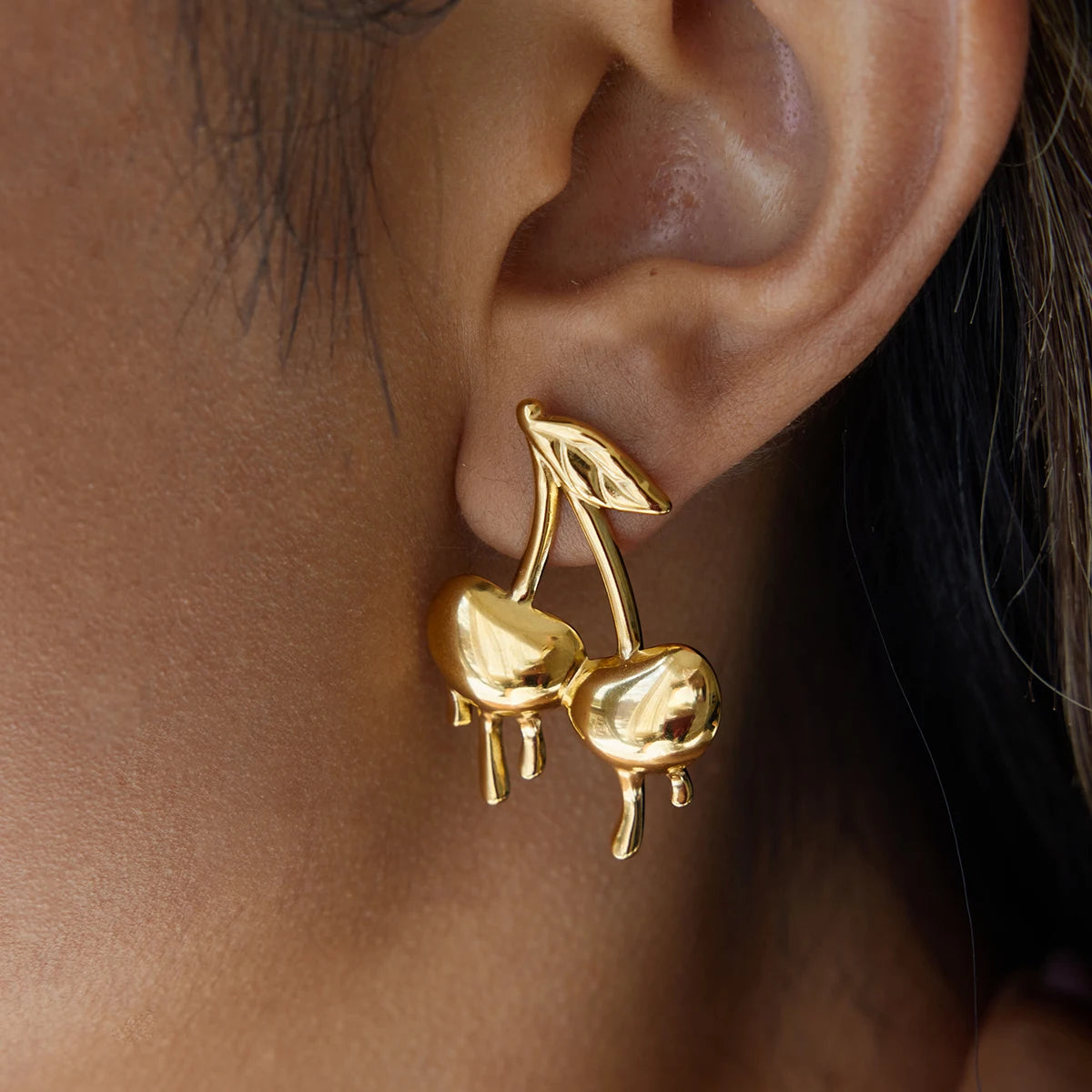 Gold-plated medical steel drop earrings in the shape of cherries with a unique melting or dripping gold effect. High-shine finish, hypoallergenic and waterproof.