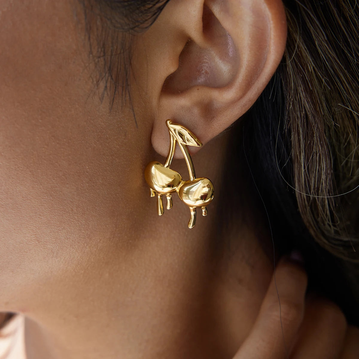 Gold-plated medical steel drop earrings in the shape of cherries with a unique melting or dripping gold effect. High-shine finish, hypoallergenic and waterproof.