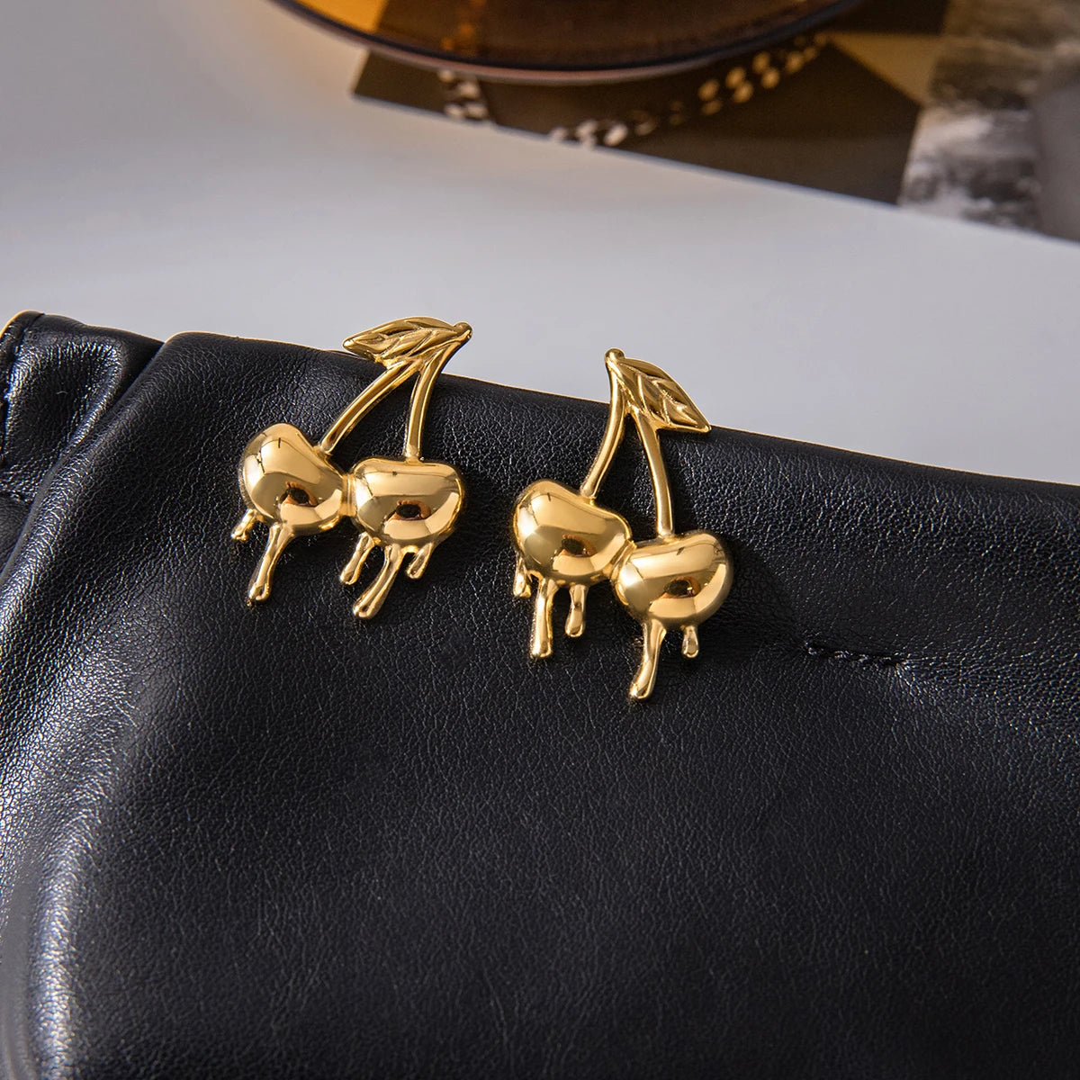 Gold-plated medical steel drop earrings in the shape of cherries with a unique melting or dripping gold effect. High-shine finish, hypoallergenic and waterproof.
