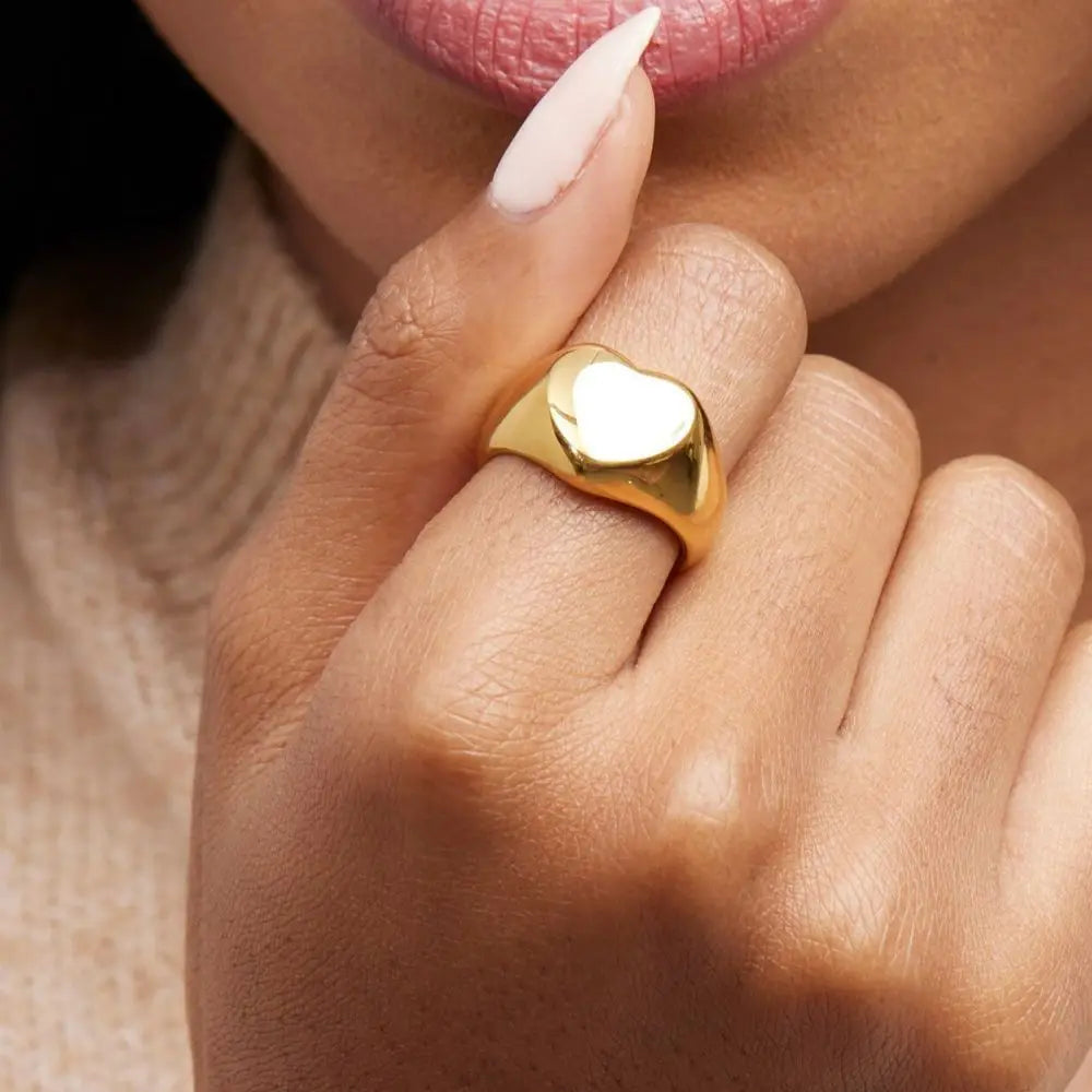 A chunky 18ct gold plated medical steel signet ring featuring a large, polished heart-shaped face. High-shine finish, hypoallergenic and tarnish-resistant.