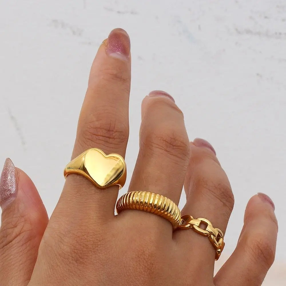 A chunky 18ct gold plated medical steel signet ring featuring a large, polished heart-shaped face. High-shine finish, hypoallergenic and tarnish-resistant.