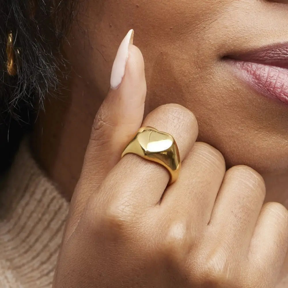 A chunky 18ct gold plated medical steel signet ring featuring a large, polished heart-shaped face. High-shine finish, hypoallergenic and tarnish-resistant.