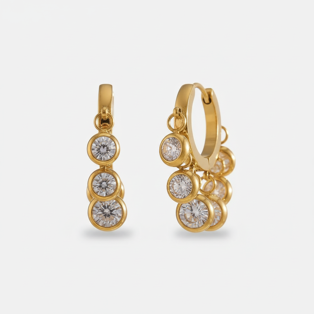 A pair of 18ct gold plated medical steel huggie hoop earrings adorned with multiple dangling round diamante crystals in polished bezel settings. Hypoallergenic and tarnish-proof jewellery.