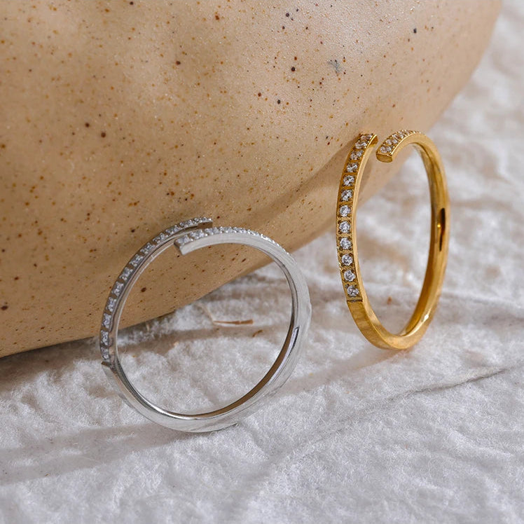 A delicate 18ct gold plated medical steel wrap ring with a bypass design, encrusted with a fine row of clear diamante crystals in a pavé setting.