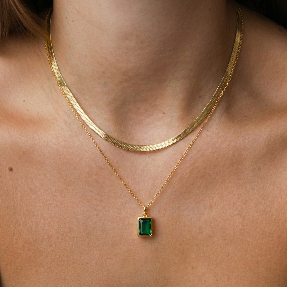 Gold necklace with a green gemstone pendant on a person's neck