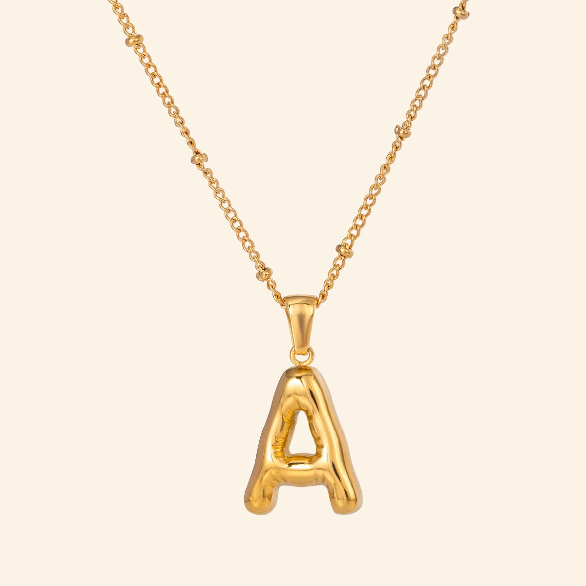 Gold necklace with a letter 'A' pendant on a white background