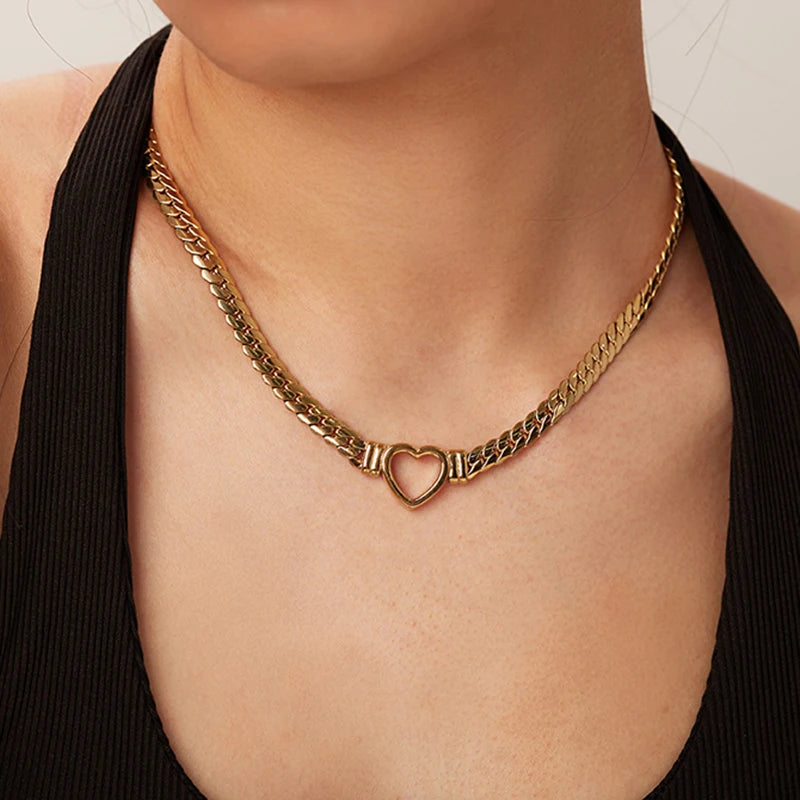 Gold chain necklace with a heart pendant on a person wearing a black top.