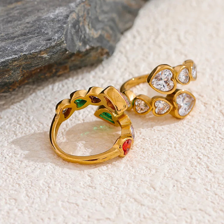 Adjustable gold-finish bypass ring adorned with clear heart-cut diamantes in a textured gold setting.