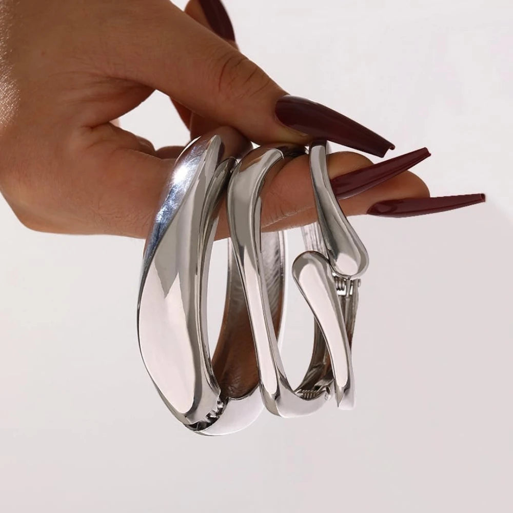 Three chunky silver-finish stackable bangles with a smooth, high-shine surface and unique curved design, displayed against a white background.