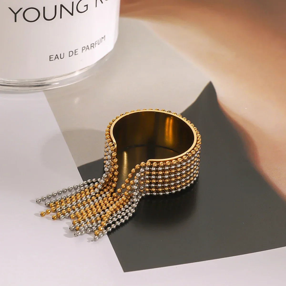 Architectural mixed-metal ring in 18k gold and silver tones, featuring a bicolour cascading ball-chain tassel for a liquid-like effect.