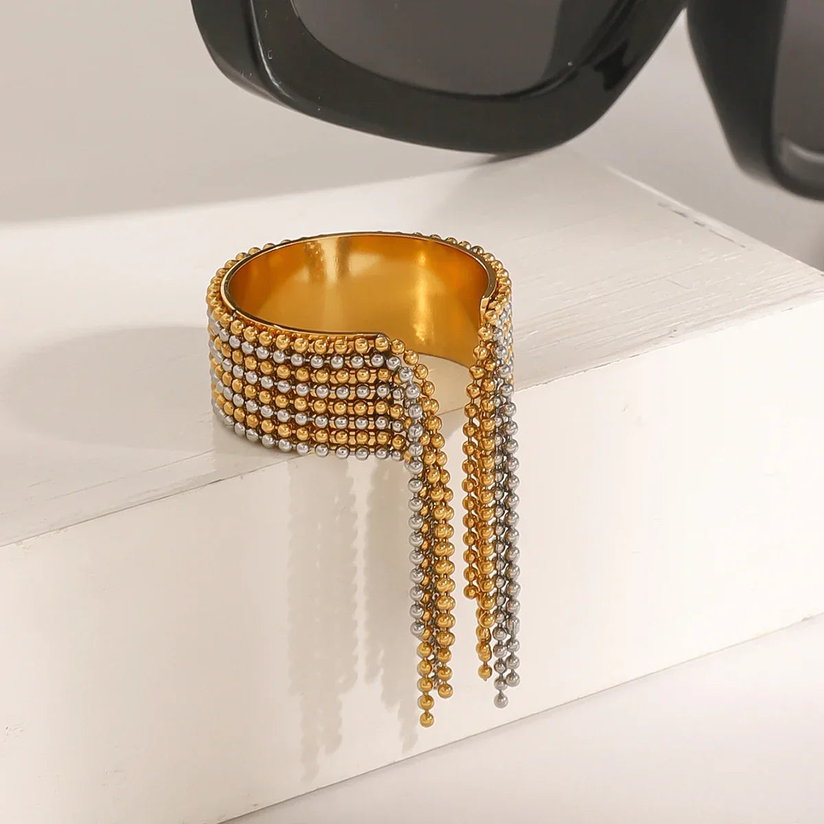 Architectural mixed-metal ring in 18k gold and silver tones, featuring a bicolour cascading ball-chain tassel for a liquid-like effect.