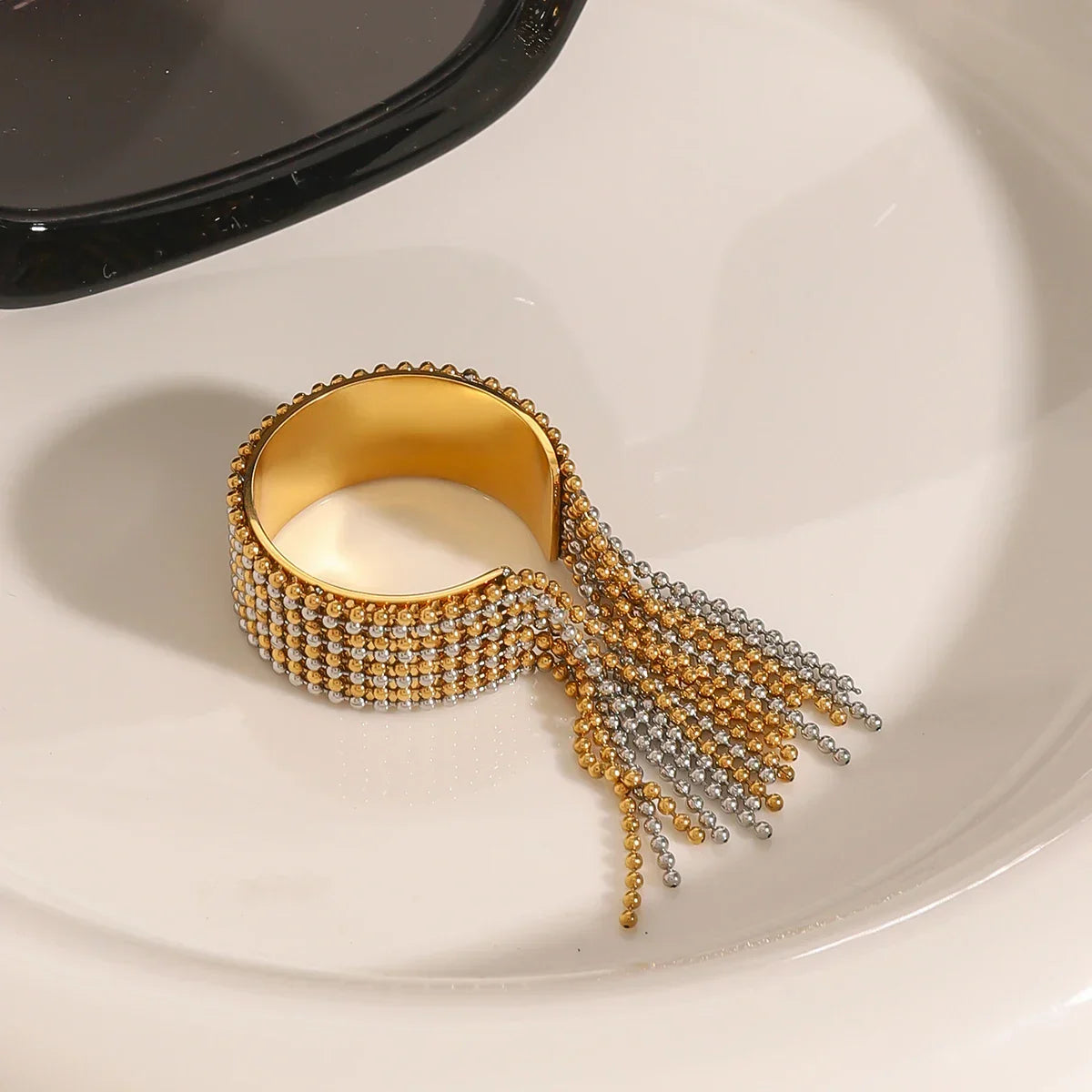 Architectural mixed-metal ring in 18k gold and silver tones, featuring a bicolour cascading ball-chain tassel for a liquid-like effect.