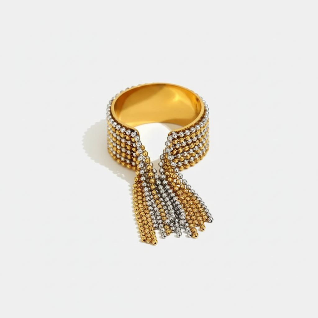 Architectural mixed-metal ring in 18k gold and silver tones, featuring a bicolour cascading ball-chain tassel for a liquid-like effect.
