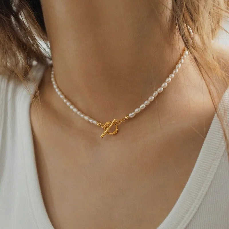 A multi-strand choker necklace featuring five rows of delicate white seed pearls and a central 18ct gold plated medical steel floral motif with an iridescent stone centre.