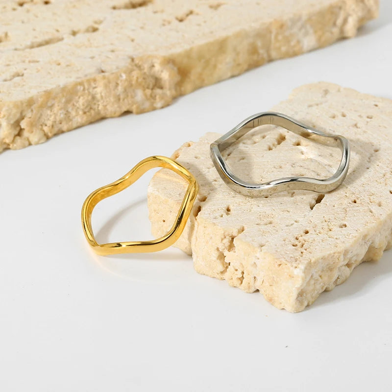 A minimalist wavy stacking ring made from 18ct gold plated medical-grade stainless steel. Features a high-shine polished finish and a fluid, organic curved shape.