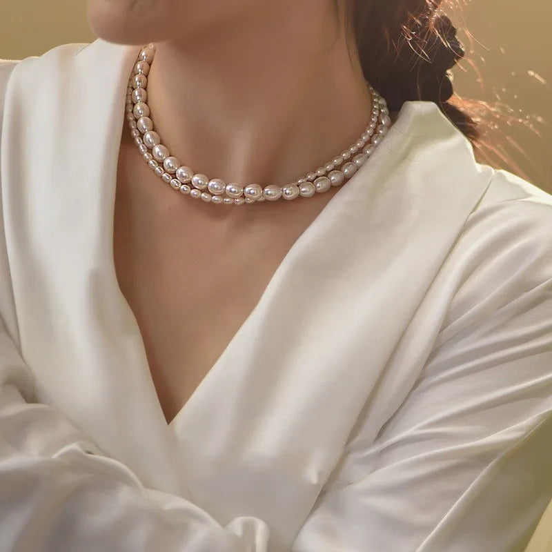 A two-strand pearl necklace featuring a wide herringbone chain and a longer fine chain with a small polished circular pendant.
